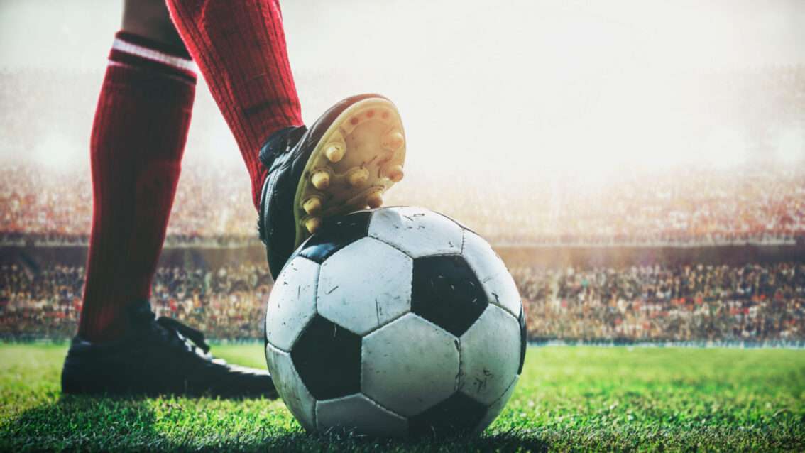 Fuß von Fußballer auf Ball im Stadion